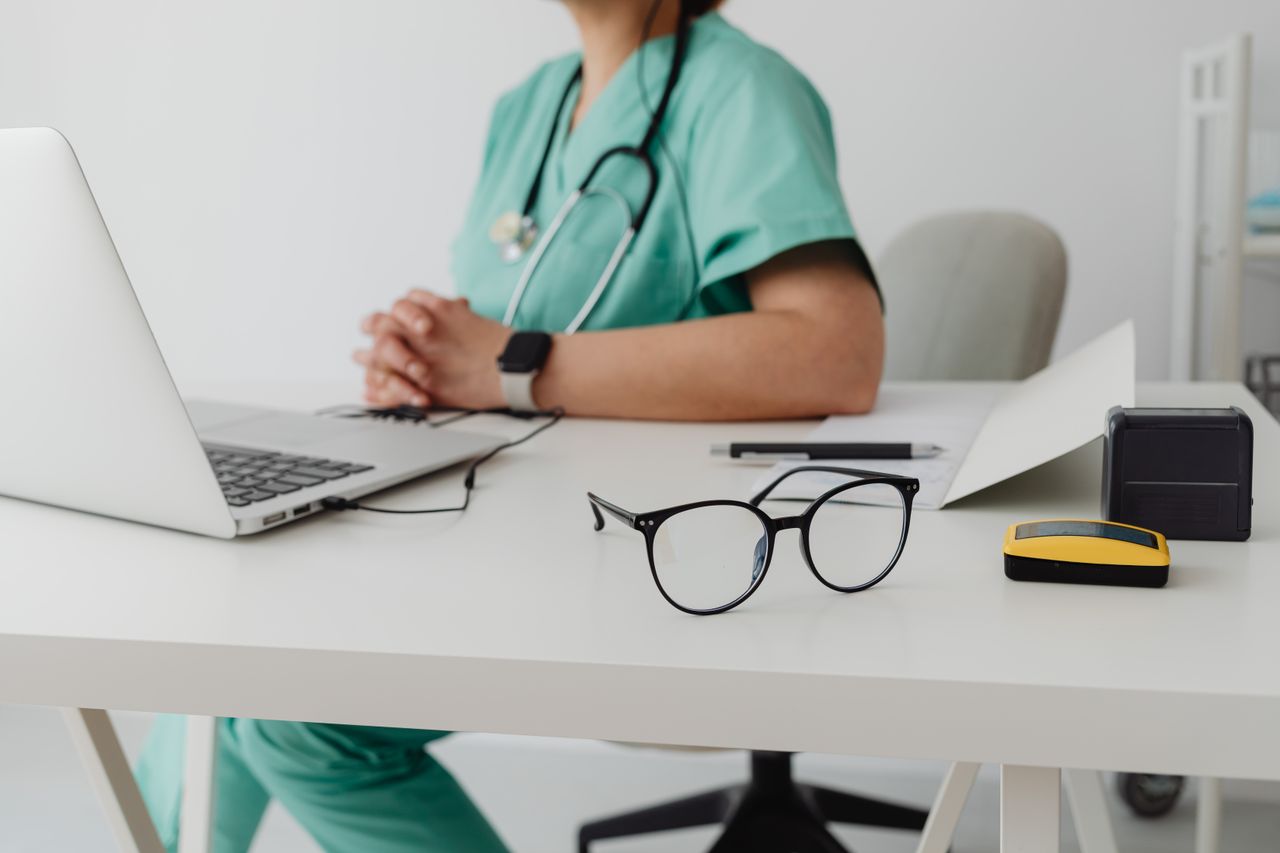Services A healthcare professional in scrubs using a laptop in an office setting.