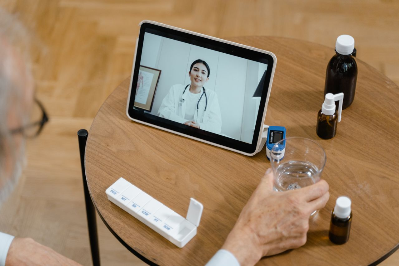 Services Senior adult having a virtual doctor consultation on a tablet with medications on the table.